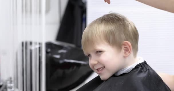 Parrucchiere tagli capelli felice sorridente bambino biondo ragazzo. Primo piano sullo stile di vita. Concetto di bellezza, igiene. — Video Stock