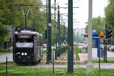 Konstal 105Na tramvayı, tepetaklak kablolar ve elektrik direklerinden oluşan karmaşık bir ağ altında durağa yaklaşıyor, Krakow, Küçük Polonya, Polonya, Avrupa.