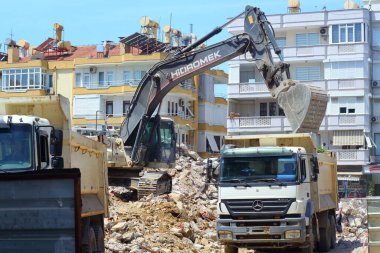 Alanya, Türkiye - Haziran 05 2019. Kazıcı ve kamyon şehirdeki evlerin yanındaki eski bir binanın yıkımı üzerinde çalışıyor..