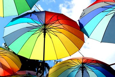 Mavi gökyüzüne karşı renkli şemsiyeler.