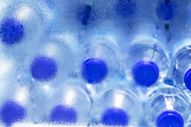 Buzdolabında plastik şişedeki soğuk su sıraları, seçici fokus..