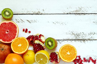 Portakal, limon, kivi, nar, greyfurt ve beyaz ahşap zemin..