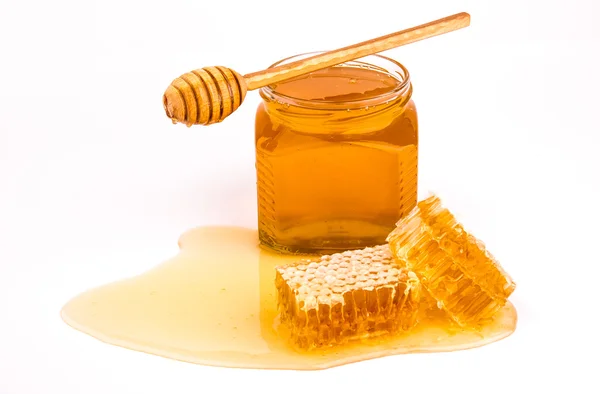 Transparent honey in bank, with honeycombs, a spoon isolated on white Royalty Free Stock Images