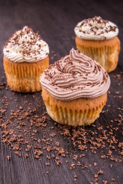 Çırpılmış krema ve çikolata tıraş koyu ahşap tahtası ile cupcakes