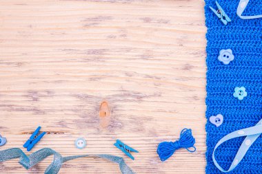 Düğmeli örgü bant, yay ve clothespegs hafif ahşap arka plan üzerinde mavi