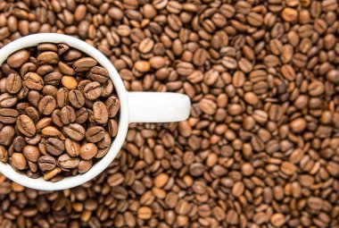 Karanlık bir arka plan beyaz bir fincan kahve taneleri