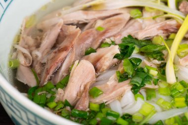 Pirinç eriştesi ve doğranmış sebzeli çorbanın içinde tavuk filetosu.