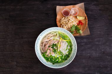 Tavuk çorbası, pirinç, beyaz erişte, doğranmış yeşil soğan, limon ve sos ile servis edilir.