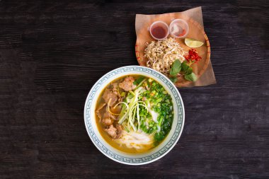 Domates ezmeli çorba, dana eti parçaları, yeşil soğan, pirinç eriştesi, acı biberle servis edilir.