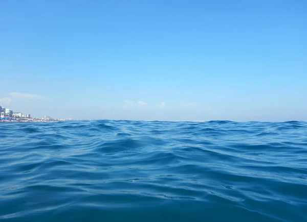 City by the Mediterranean sea with big waves always on. Very bright day. Very blue water and sky