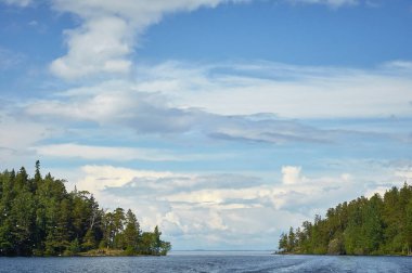 sky with clouds over the water. a trace of a boat on the water surface, waves.