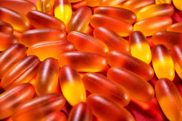 pattern of yellow gelatin capsules on a red background. omega viramins, close-up, macro