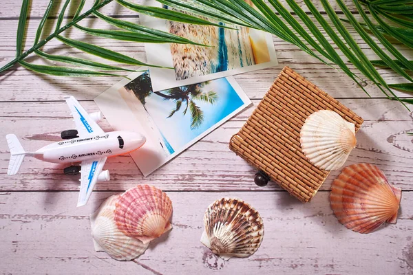 Composition of colorful souvenirs, palm leaves and seashells with a Straw gift box on wooden background. Summer beach and travel.  Top view with copy space.