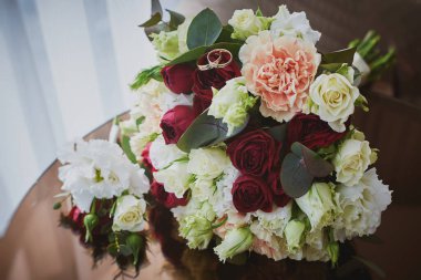 Otel odasındaki gelin buketinin üzerindeki alyansların yakın görüntüsü.. 