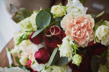 Otel odasındaki gelin buketinin üzerindeki alyansların yakın görüntüsü.. 