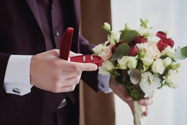 Mãos Homem Segurando Uma Caixa Alianças Vermelhas Buquê Casamento Preparativos — Fotografia de Stock