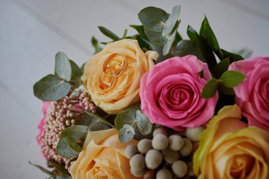 Altın yüzükler ve arka planda güzel bir gül buketi. Detaylar, düğün gelenekleri. Yakın çekim, makro