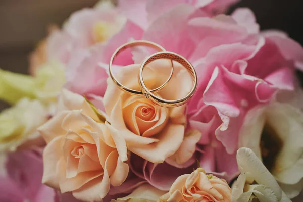 Χρυσά Δαχτυλίδια Και Ένα Όμορφο Νυφικό Μπουκέτο Τριαντάφυλλα Στο Παρασκήνιο — Φωτογραφία Αρχείου
