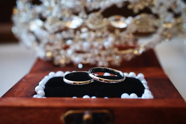 İncilerle süslenmiş ahşap bir kutuda gümüş alyanslar. Eski arkaplan