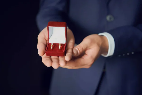 金光闪闪的结婚戒指装在红色礼品盒里 还有一束白玫瑰做的新娘花束 特写镜头 — 图库照片