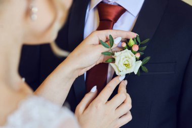 Gelin takım elbisesinin yaka çiçeğini ayarlıyor. Düğüne hazırlanıyorum. Yakın çekim, makro