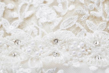 Boncuklarla, yapay elmaslarla ve pullarla işlenmiş bir gelinlik dokusu. Yakın çekim, makro