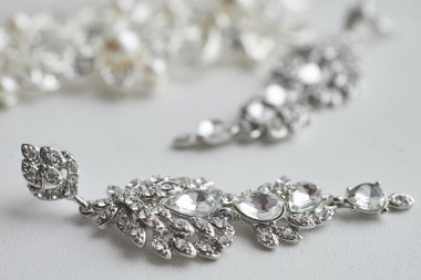 Beyaz arka planda kristallerden ve yapay elmaslardan yapılmış lüks küpeler. Düğün aksesuarları. Yakın çekim, makro