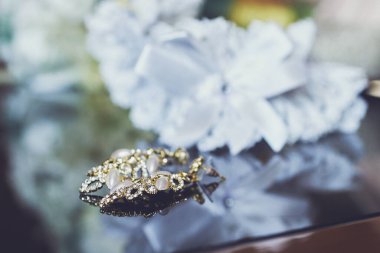 Kristallerden ve yapay elmaslardan yapılmış lüks küpeler ve cam masanın üzerinde gelinin jartiyeri. Düğün aksesuarları. Yakın çekim, makro