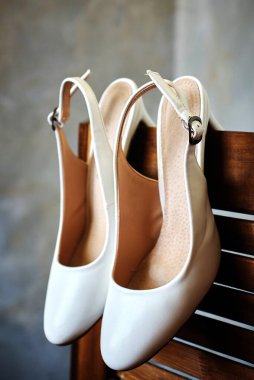Tahta bir ekranda bir çift zarif beyaz gelinlik ayakkabısı. Düğün hazırlıklarının detayları. Yakın çekim, makro