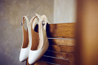 Tahta bir ekranda bir çift zarif beyaz gelinlik ayakkabısı. Düğün hazırlıklarının detayları. Yakın çekim, makro