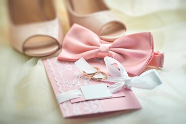 Altın alyanslar, davetiye kartı, pembe papyon, gelin ayakkabıları. Düğün hazırlıklarının detayları. Yakın çekim, makro