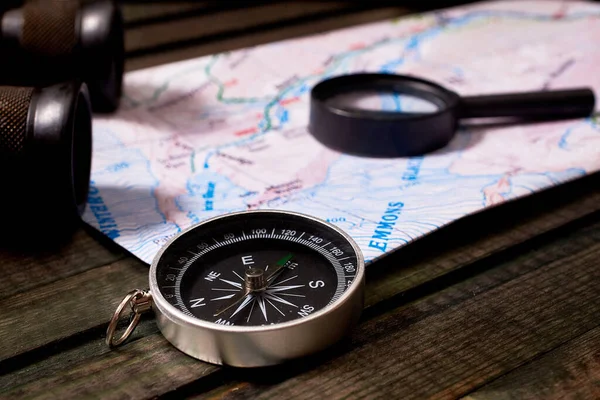 travel kit: vintage binoculars, map, compass,  on wooden background. close-up, macro