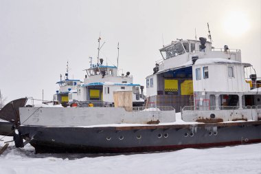 Buz kaplı nehirde karla kaplı feribotlar.