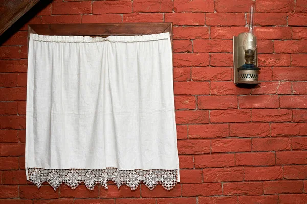 Evin duvarında perdeli bir pencere ve gazyağı lambası var. Eski arkaplan