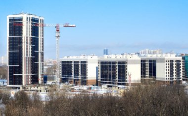 İnşaat vinci ve şehrin arka planında yeni binalar. Kışın inşaat alanı.