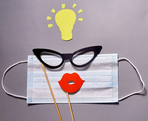 Medical mask with glasses and lips and yellow paper light bulb s