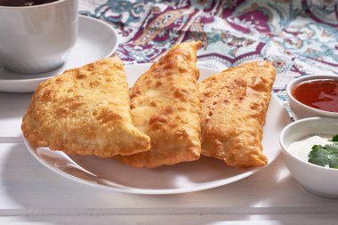 Lezzetli cheburekler (etle birlikte calzone) beyaz ahşap arka planda soslar ile.