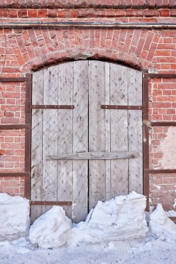Eski tuğla bir duvarda ahşap bir kapı. Terk edilmiş bir binanın ayrıntıları.