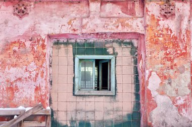 Terk edilmiş bir sanayi binasının eski tuğla duvarında parmaklıklı bir pencere. Yıkımın estetiği.