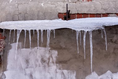 Birçok büyük buz sarkıtları eski bir tuğla binanın çatısında asılı..
