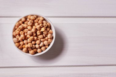 Beyaz ahşap arka planda beyaz bir kasede nohut tohumları. Yakın çekim, makro, kopyalama alanı