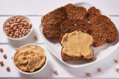 Nohut ve nohut tabağı-humus, beyaz ahşap arka planda ezmeli tam tahıllı ekmek. Sağlıklı beslenme. Yakın plan..