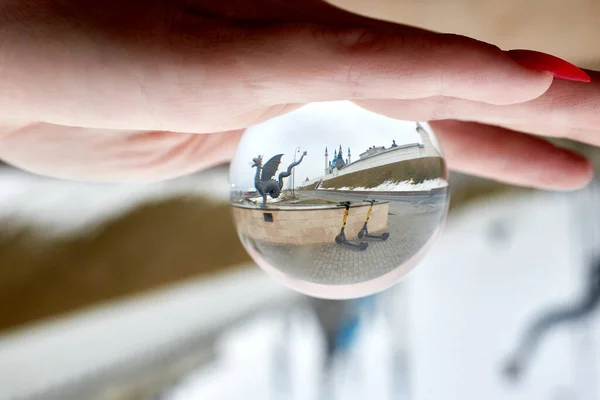 A glass ball with a reflection of the sights. Optical illusion, effect. Close-up, macro