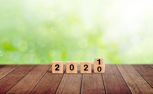 2020 change to 2021. Wooden blocks new year dice on a natural blurred background. Wood block numbers on wood table. Creative Concept