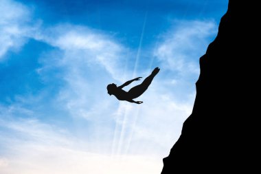 man silhouette diving from top of the cliff in sunny day and blue sky.	