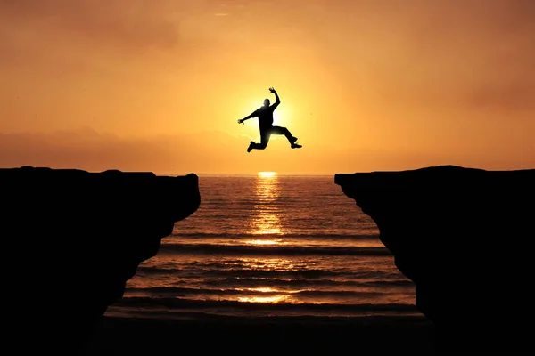 Valiente Joven Saltando Sobre Acantilado Silueta Sunset Background Objetivo Negocio Imagen De Stock