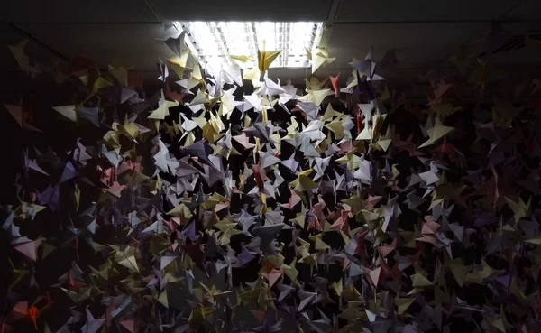 Kleurrijke origami kraanvogels op plafond snaren onder licht lamp — Stockfoto