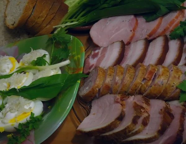 Osterfleisch-Leckereien. hausgemachte Würstchen, Schweinebauch und Speck mit grünen Waren und gekochten Eiern — Stockfoto