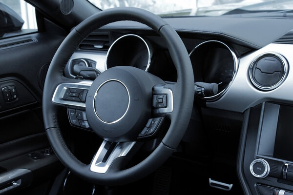 Dashboard and multifunction steering wheel in leather car interior 