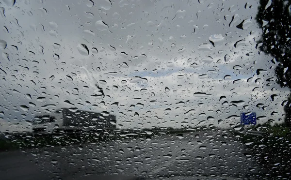 Mira en el camión en la carretera a través del parabrisas húmedo con gotas de lluvia — Foto de Stock